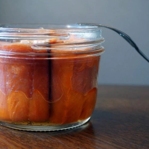 Jar of pickled salmon with a fork on a wooden surface